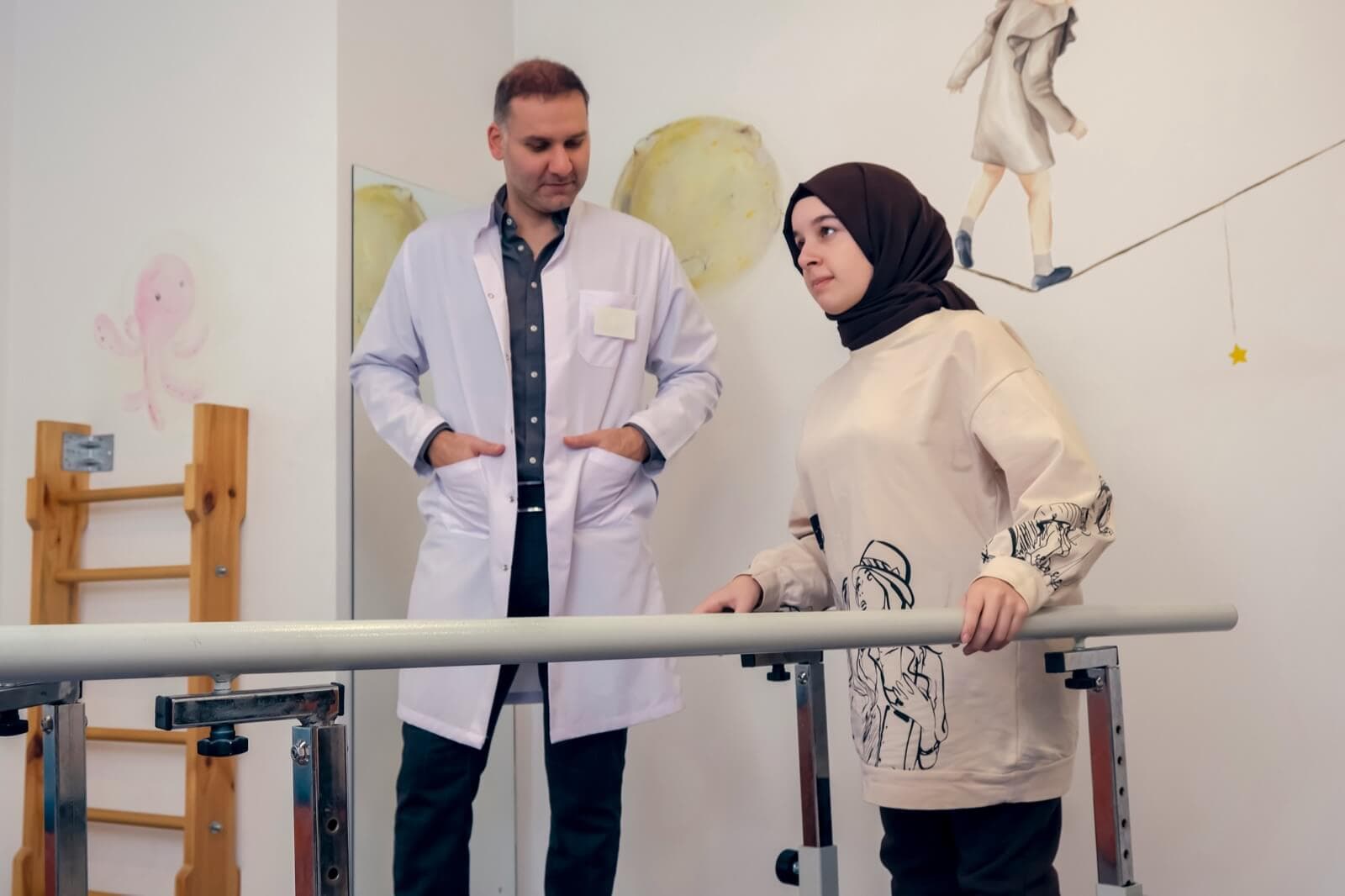 Fysiotherapeut begeleidt patiënt bij looptraining tussen de brugleuningen in de revalidatieruimte