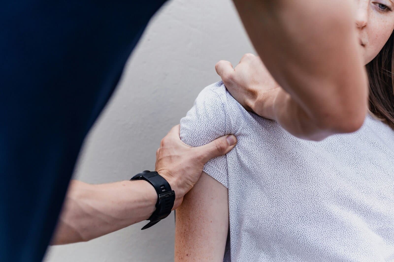 Fysiotherapeut onderzoekt de schouder van een patiënt door palpatie tijdens een behandeling