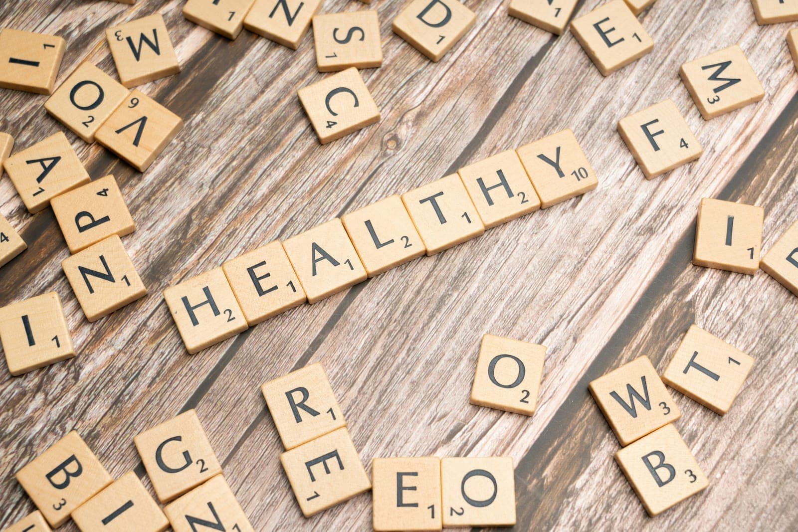 Houten letterblokjes op een verweerde plank vormen het woord healthy